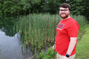 Tanner standing at a pond, getting ready to go fishing with a pole in hand