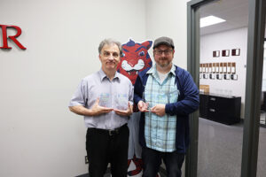Two men holding awards happily.